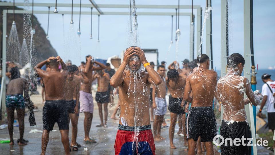 Migranten duschen in einer Anlage am Strand von El Trampolín in der spanischen Exklave Ceuta, wo zahlreiche provisorische Unterkünfte errichtet wurden. Bild: Marcos Moreno/EUROPA PRESS/dpa