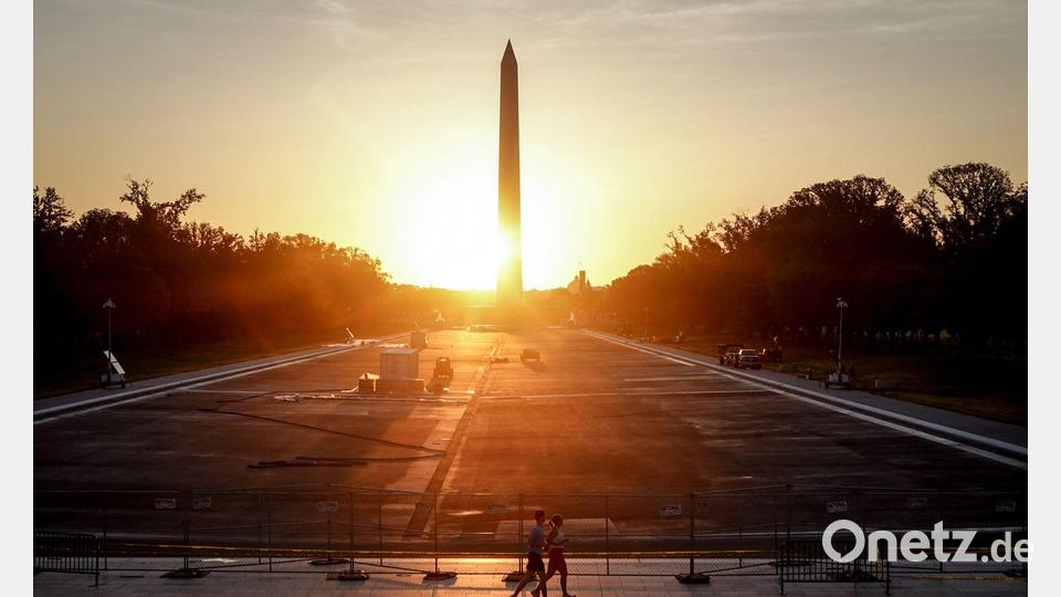 Passanten laufen am Morgen im Sonnenaufgang an dem trockengelegten Reflecting Pool vorbei. Bild: Kay Nietfeld/dpa