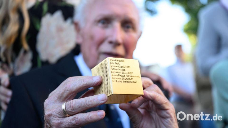 Der Münchner Toni Heilmaier, der zufällig entdeckte, dass seine Großmutter Anna Paroubek Holocaust-Opfer wurde, hält ein Erinnerungszeichen in den Händen. Bild: Lukas Barth-Tuttas/dpa