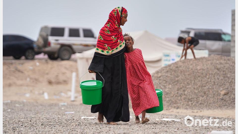 Binnenflüchtlinge im Jemen: Zwei jemenitische Mädchen, die ihre Heimat verlassen mussten, tragen Eimer durch das Lager, in dem sie jetzt leben. Bild: Abdulnasser Alseddik/AP/dpa