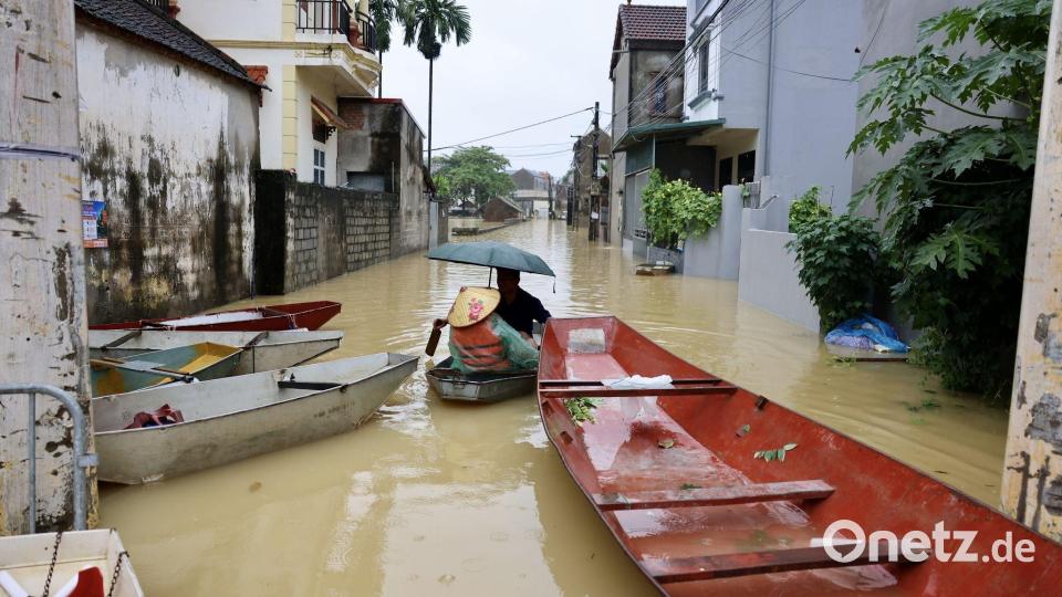 Anwohner fahren mit einem Boot durch ein überflutetes Dorf in Vietnam. Bild: Nhat Anh/VNA/AP/dpa