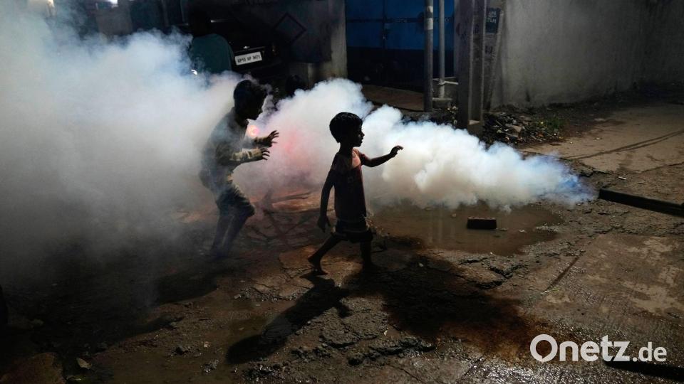 Kinder spielen inmitten der Dämpfe, die entstehen, als ein Mitarbeiter der Stadtverwaltung von Hyderabad ein Wohngebiet ausräuchert, um die Ausbreitung von durch Mücken übertragenen Krankheiten zu verhindern. Bild: Mahesh Kumar A./AP/dpa
