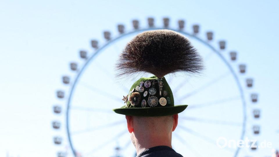 Oktoberfest 2026: ein Mann mit Gamsbart steht am ersten Wiesn Tag vor dem Riesenrad. Bild: Karl-Josef Hildenbrand/dpa