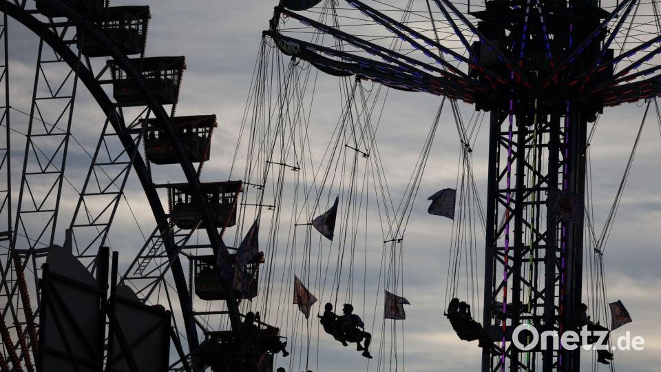 Wiesn-Besucher sitzen am Abend in einem Karussell vor dem Riesenrad auf dem Oktoberfest. Bild: Karl-Josef Hildenbrand/dpa