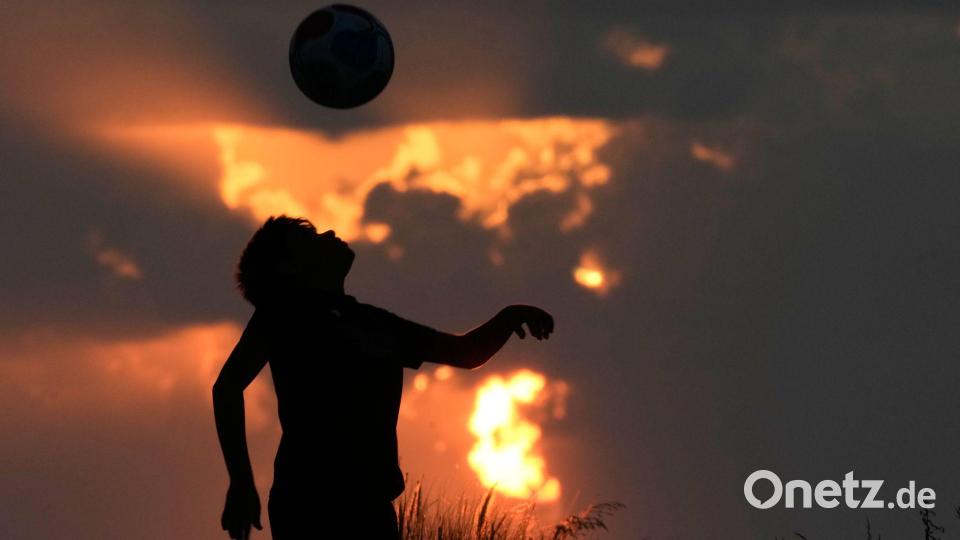 Ein Junge spielt Fußball, während die Sonne über der Mittelmeerküste in Beirut untergeht. Bild: Bilal Hussein/AP/dpa