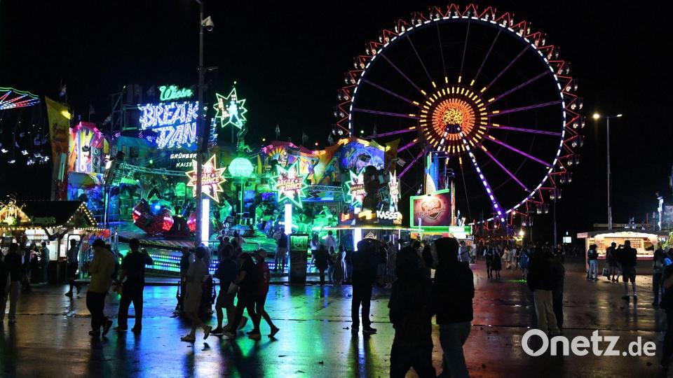 Wiesnbesucher gehen bei Regen über das Oktoberfest. Bild: Felix Hörhager/dpa