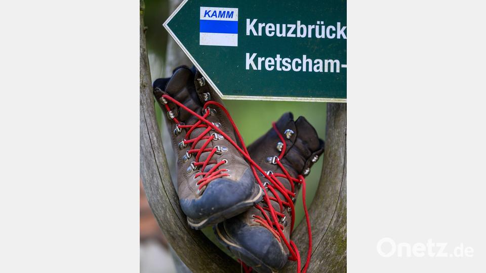 Wanderschuhe stehen in einem Wegweiser am Fuß des Fichtelbergs. Bild: Hendrik Schmidt/dpa