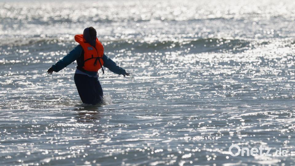Ein Migrant läuft in Nordfrankreich im Meer nahe der Küste, während er versucht, den Ärmelkanal mit einem Schlauchboot von Frankreich nach Großbritannien zu überqueren. Bild: Jean-Francois Badias/AP/dpa