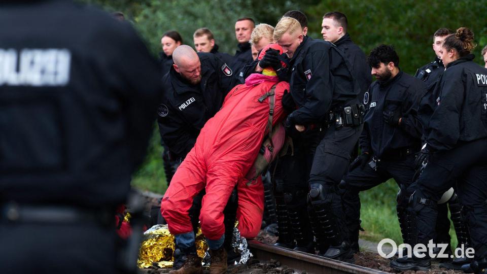 Polizisten räumen eine Gleisblockade im Hamburger Hafen, mit der Aktivisten gegen steigende Militärausgaben protestieren. Bild: Marcus Golejewski/dpa