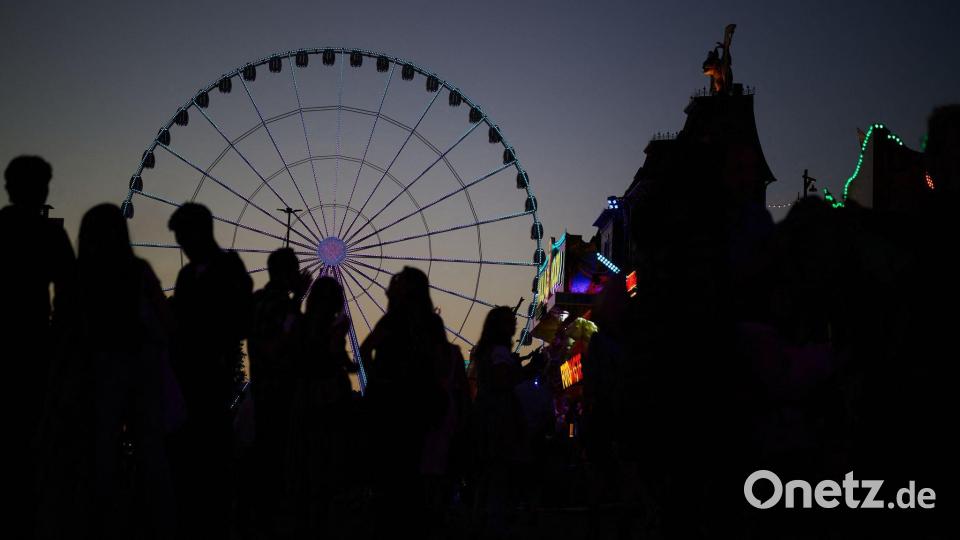 Besucher zeichnen sich vor einem Riesenrad auf dem Cannstatter Volksfest ab. Bild: Marijan Murat/dpa