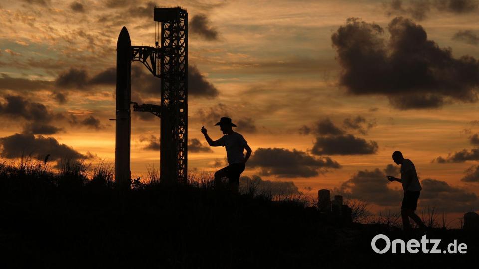 Bei Sonnenuntergang versammeln sich Menschen vor der Mega-Rakete „Starship“. Bild: Eric Gay/AP/dpa