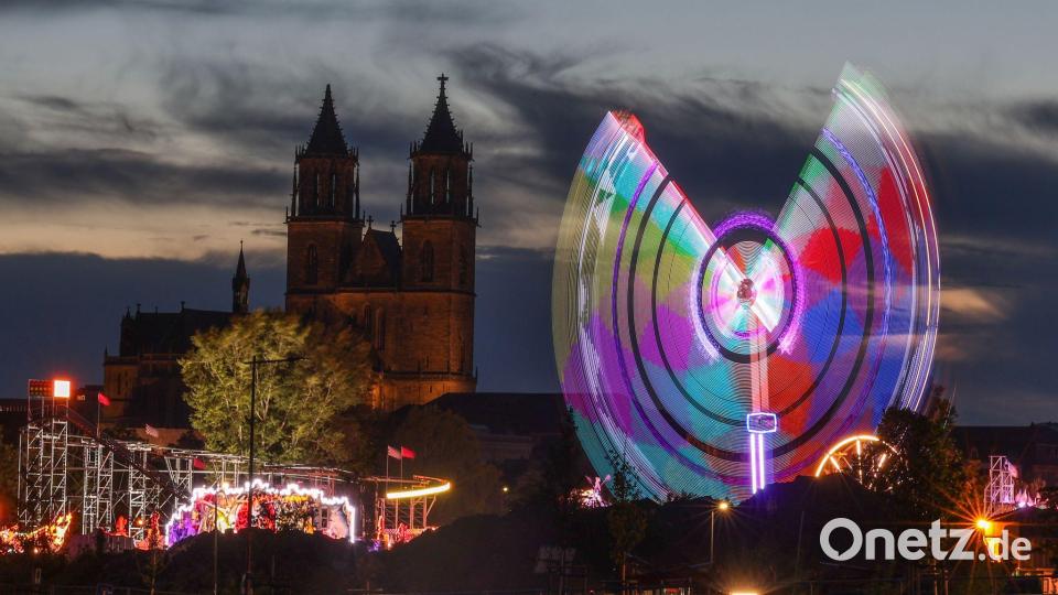 Das Fahrgeschäft "Eclipse" dreht sich am Abend vor dem Magdeburger Dom auf der 1016. Magdeburger Herbstmesse. Bild: Peter Gercke/dpa