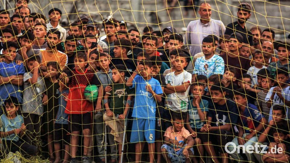 Menschen verfolgen ein Fußballspiel zwischen einer Mannschaft aus Gaza gegen eine Mannschaft aus Chan Yunis auf einem Gelände zwischen Zelten, in denen Binnenflüchtlinge untergebracht sind. Bild: Abedrahim Khatib/dpa