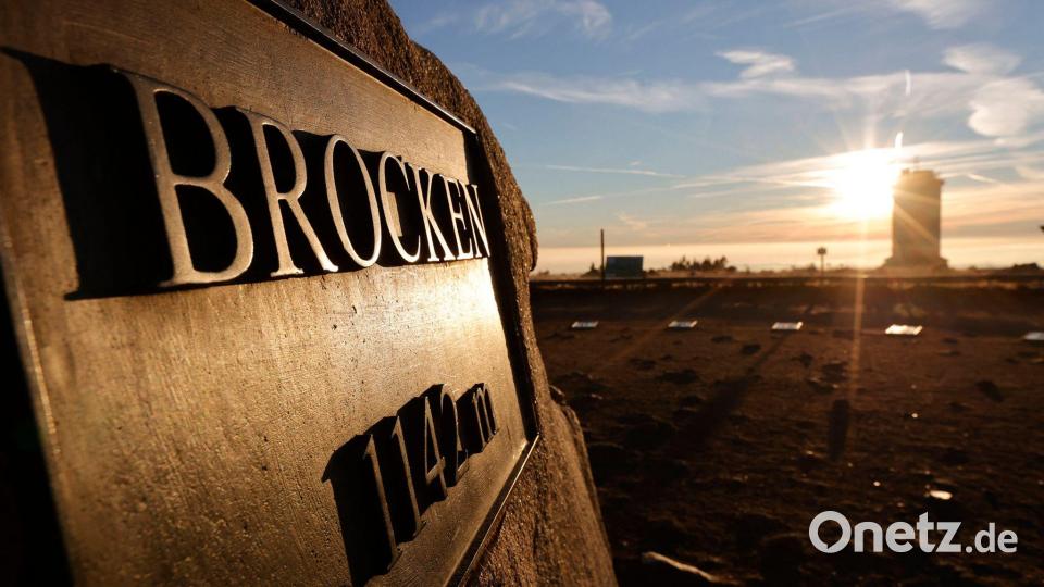 Das Licht der aufgehenden Sonne reflektiert auf einer Tafel mit der Aufschrift "Brocken" am höchsten Punkt des Brockens. Bild: Matthias Bein/dpa