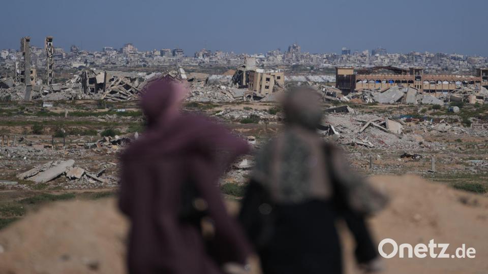 Frauen blicken auf ein stark zerstörtes Gebiet im Zuge des Gaza-Kriegs. Bild: Abdel Kareem Hana/AP/dpa