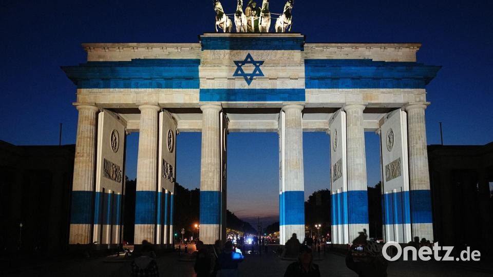 Teilnehmer stehen vor dem mit der Fahne Israels angestrahlten Brandenburger Tor und gedenken bei der Veranstaltung zum Jahrestag des Terrorangriffs der Hamas auf Israel am 7. Oktober 2023 den Opfern. Bild: Kay Nietfeld/dpa