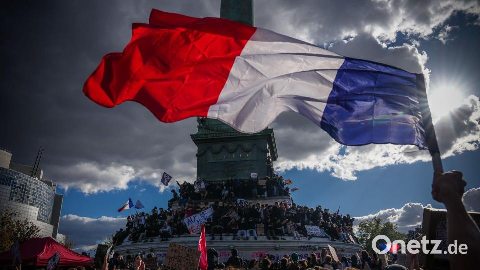 Eine Person hält bei einer Demonstration in Paris gegen unterfinanzierte Schulen eine französische Nationalfahne. Bild: Aurelien Morissard/AP/dpa