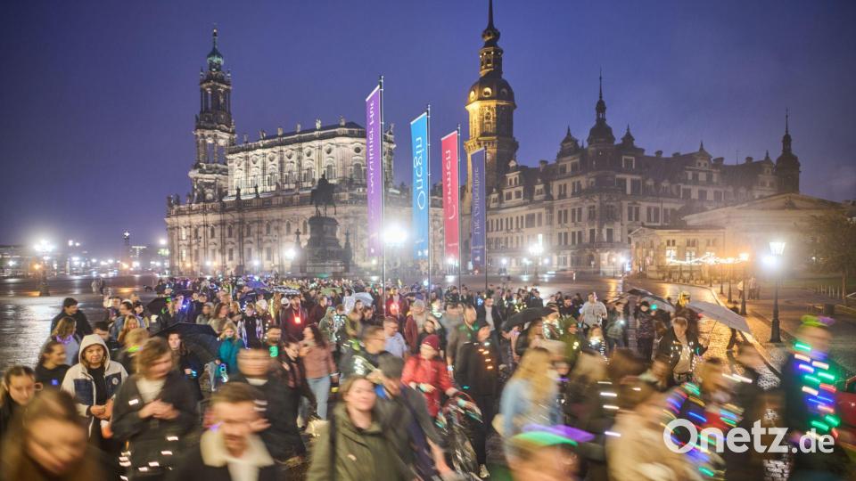Teilnehmer des Spazierclubs laufen am Abend durch Dresden. Bild: Robert Michael/dpa