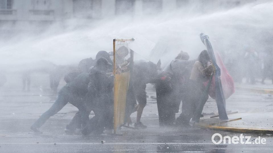 Demonstranten in Buenos Aires suchen Deckung, während die Polizei bei einer regierungskritischen Demonstration einen Wasserwerfer einsetzt. Bild: Rodrigo Abd/AP/dpa