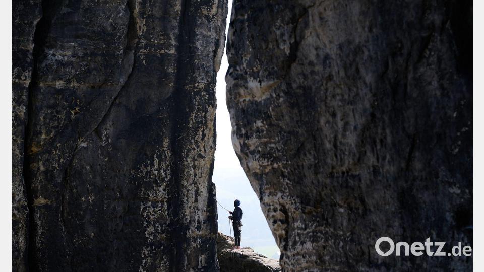 Zwischen zwei Felsen: Ein Kletterer sichert eine Kletterin am Felsen an der Basteibrücke in der Sächsischen Schweiz ab. Bild: Katharina Kausche/dpa