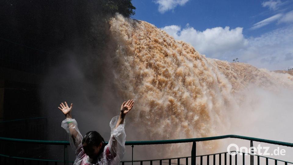 Hände hoch vor den Wassermassen der Iguazú-Wasserfälle in Brasilien Bild: Jorge Saenz/AP/dpa