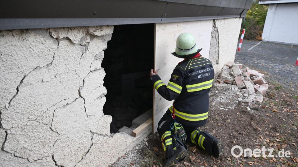 Ein Feuerwehrmann deckt das Loch in der Garagenwand ab. Bild: Felix Hörhager/dpa