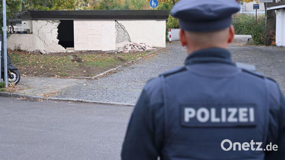 Ein Polizist betrachtet die beschädigte Garagenwand. Bild: Felix Hörhager/dpa