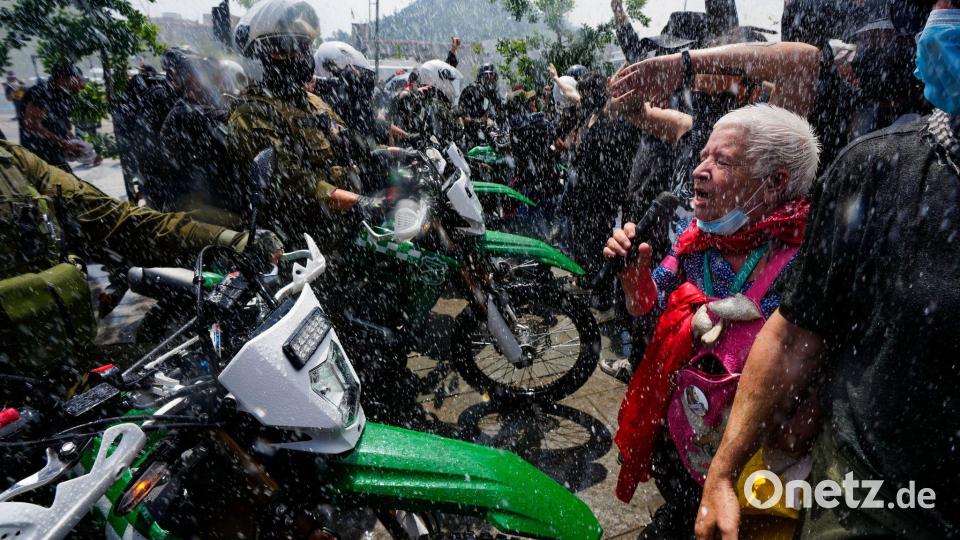 Die Polizei setzt während eines Marsches anlässlich des 7. Jahrestags des sozialen Aufstands in Chile im Jahr 2019 einen Wasserwerfer ein, um Demonstranten zu vertreiben, die gegen geplante Ausgabenkürzungen der Regierung protestieren. Bild: Esteban Felix/AP/dpa