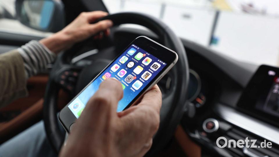 Sorgt für Ablenkung beim Fahren und dadurch immer wieder für Unfälle: das Smartphone am Steuer. (Illustration) Bild: Karl-Josef Hildenbrand/dpa