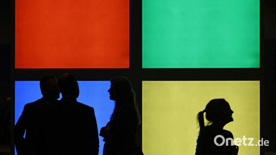 Besucher stehen auf der Microsoft AI Tour in Köln vor dem Logo des Unternehmens. Microsoft macht mit seiner Werbe-Tour für künstliche Intelligenz Station in Köln. Bild: Oliver Berg/dpa