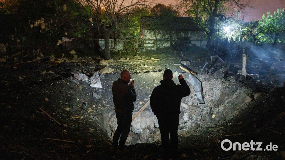 Menschen betrachten einen Krater. Bild: Evgeniy Maloletka/AP/dpa