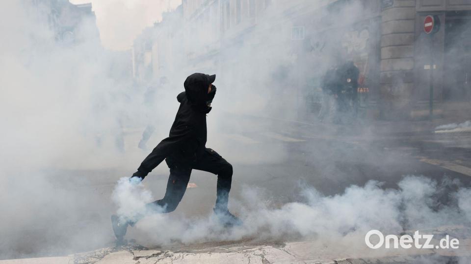 Ein Demonstrant wirft in Rennes eine Tränengasgranate in Richtung der Polizei. Bild: Jeremias Gonzalez/AP/dpa