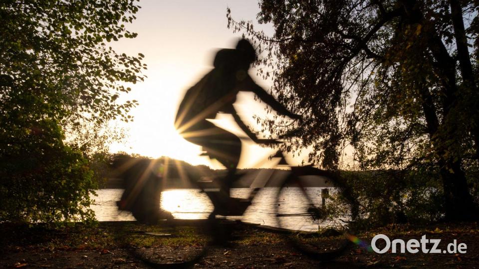 Ein Fahrradfahrer fährt bei Sonnenaufgang am Ufer des Templiner Sees entlang. Bild: Georg-Friedrich Moritz/dpa