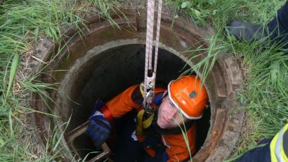 Korbinian Kraus lässt sich in den dunklen Kanal abseilen, um einer abgestürzten Person zu helfen.