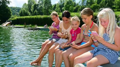 Immer die Finger am Smartphone: Am Freitag kühlten sich die Königsteiner im Naturbad ab und stimmten im Netz für ihre Heimat ab, damit das Bayern-3-Dorffest kommt.	Bild: Hartl
