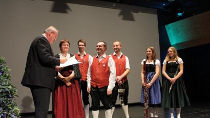 Bezirkstagspräsident Franz Löffler übergibt Vorsitzender Angela Harbauer und Dirigent Stefan Neger den Kulturpreis des Bezirks.