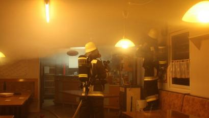 Die Löscharbeiten in der großen Holzhütte Hinterm Rehbühl gestalten sich schwierig. In den völlig verrauchten Räumen müssen die Feuerwehrleute Teile von Wand und Decke aufsägen.

	Bild: R. Kreuzer