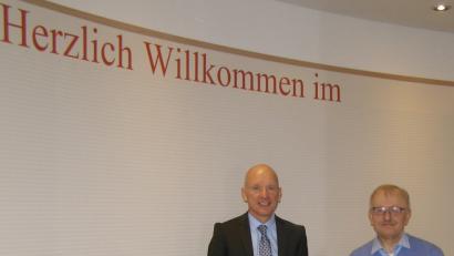 Kewog-Chef Bernd Büsching und Hotel-Geschäftsführer Ernst Schöppl im Foyer des Appartementhotels, vor der Wand mit Willkommensgruß. 	Bild: pz