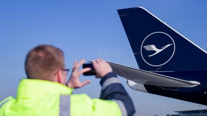 Ein Flughafenmitarbeite fotografiert am Donnerstag auf dem Hamburger Flughafen eine Boeing 747-8 der Lufthansa mit dem neuen Kranich-Logo.	Bild: Axel Heimken/dpa