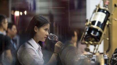 Eine Besucherin der Weinmesse in Hong Kong steht vor einem Stand und probiert einen Wein. Immer häufiger greifen die Chinesen zu guten Tropfen aus deutschen Anbaugebieten. 	Bild: Jerome Favre/dpa