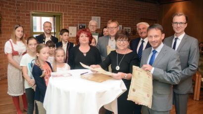 Silvia Bäumler, Schulleiterin der Clausnitzer-Grundschule (vorne, Zweite von rechts), erhält die Urkunde zur zehnjährigen Partnerschaft mit der ZS- Kolstelni-Schule in Tachov. Dazu gratuliert auch Bürgermeister Jens Meyer (vorne, rechts).	Bild: Schönberger