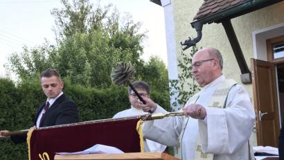 Pfarrer Wilhelm Bauer segnet die neue Fahne der Katholischen Landjugendgruppe Großenschwand. Fahnenträger Rafael Wurzer (links) und Diakon Norbert Hammerl beobachten das Geschehen.  	Bild: eig