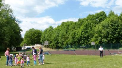 Auf dem Gelände des Schulsportplatzes mit der Laufbahn und der angrenzenden Wiese wird in naher Zukunft ein Parkplatz mit rund 150 Stellplätzen für die Studenten und Lehrkräfte der Polizeifachhochschule Kastl entstehen. Derzeit nutzen die Kindergartenkinder das Gelände noch als Spielwiese und Bürgermeister Stefan Braun (rechts) studiert den Landschaftsplan.  	Bild: jp