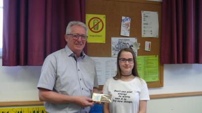 Klassensprecherin Laura Seelk überreicht im Namen der Klasse an Franz Malzer eine Schokoladentafel mit dem Schriftzug "Danke". 
	Bild: exb