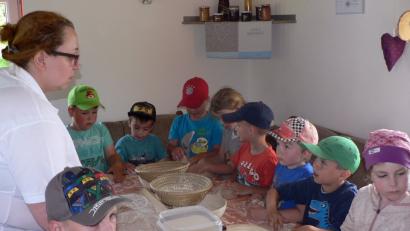 Das Brotbacken in Tagmanns macht den Vorschulkindern des Kinderhauses St. Elisabeth großen Spaß. Vom Korn bis zum fertigen Brot: Diesen Weg und die dafür erforderlichen Herstellungsschritte zeigt Monika Eisend-Speckner (links) den Mädchen und Buben. Diese dürfen auch selbst kneten und bekommen als Belohnung am Ende ihr eigenes Brot mit nach Hause.	Bild: lep