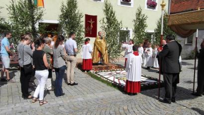 Bild: hl
An jeden der drei Altäre segnet Pfarrer Heribert Stretz (hinten) die Gläubigen mit der Monstranz. Die jeweiligen Blumenteppiche legen Frauen aus Köglitz.