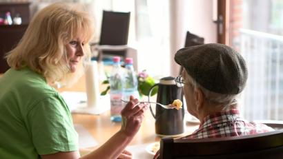 Bild: Holger Hollemann/dpa
Eine Pflegerin betreut einen älteren Mann während des Frühstücks in einem Seniorenpflegeheim.