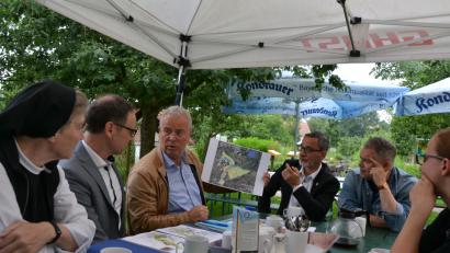 Bild: pz
Unter einem Pavillon im Naturerlebnisgarten erläuterten Bürgermeister Bernd Sommer und Landschaftsarchitekt Raimund Böhringer noch einmal das fertige Bewerbungskonzept für die Gartenschau. Von links Äbtissin Laetitia Fech, Bürgermeister Bernd, Sommer, Raimund Böhringer, Oberbürgermeister Zdeněk Hrkal und Bürgermeister-Stellvertreter  Michael  Pospíšil sowie Johanna Härtl, Leiterin der Stiftung Kultur- und Begegnungszentrum Abtei Waldsassen.