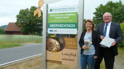 Bild: Portner
Bürgermeister Heinz Weigl und Sigrid Breitschafter freuen sich über die gelungene Werbetafel, die an allen Ortseingängen auf das Goldvorkommen hinweist. Zum Lehrpfad wurde ein neuer Flyer erstellt und im Buch „Auf den Spuren des bayerischen Goldes“ ist Oberviechtach hervorragend dargestellt.