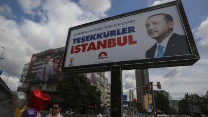 Bild: Emrah Gurel/AP/dpa
Ein Plakat mit einem Bild des Staatspräsidenten Erdogan ist ein Tag nach den Wahlen in der Türkei vor einem bewölkten Himmel zu sehen. Trotz Manipulationsvorwürfen der Opposition hat sich der türkische Staatspräsident noch vor dem Ende der Auszählung zum Sieger der Präsidentenwahl erklärt.